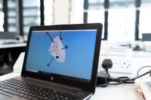 Laptop in an office environment displaying 3D design software on screen, emphasizing technology and creativity.