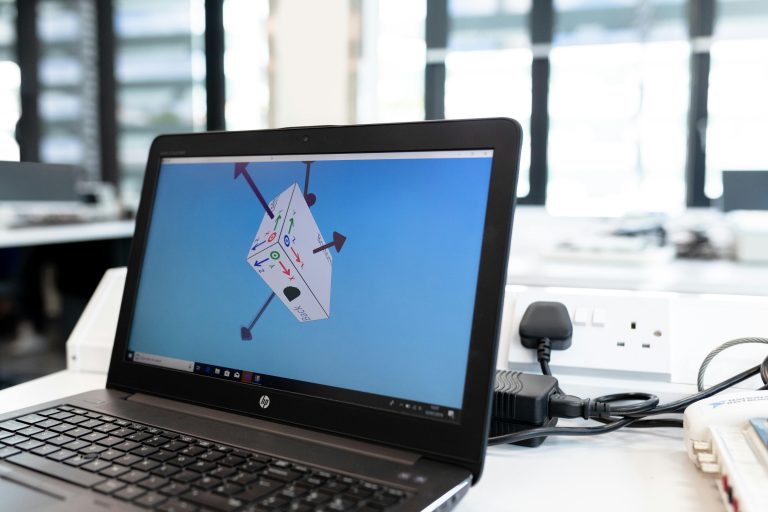 Laptop in an office environment displaying 3D design software on screen, emphasizing technology and creativity.